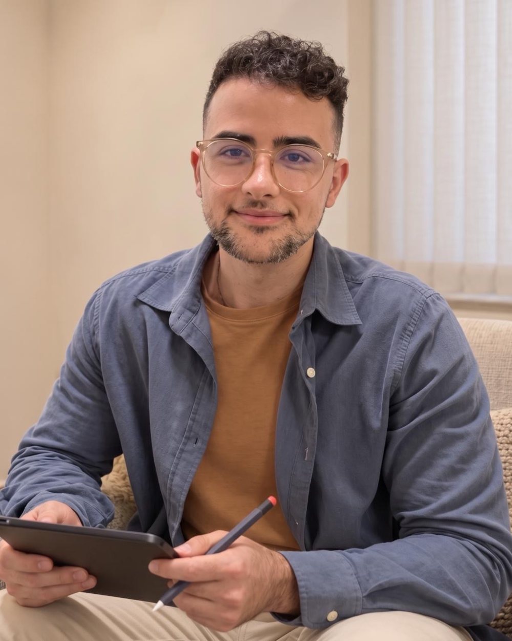 Antonio Andrade sentado em poltrona clara, de camisa azul, com tablet e caneta nas mãos